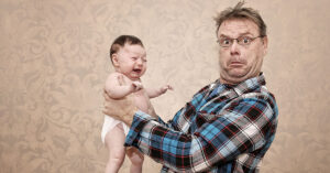 A man holding a baby and pointing at the camera.