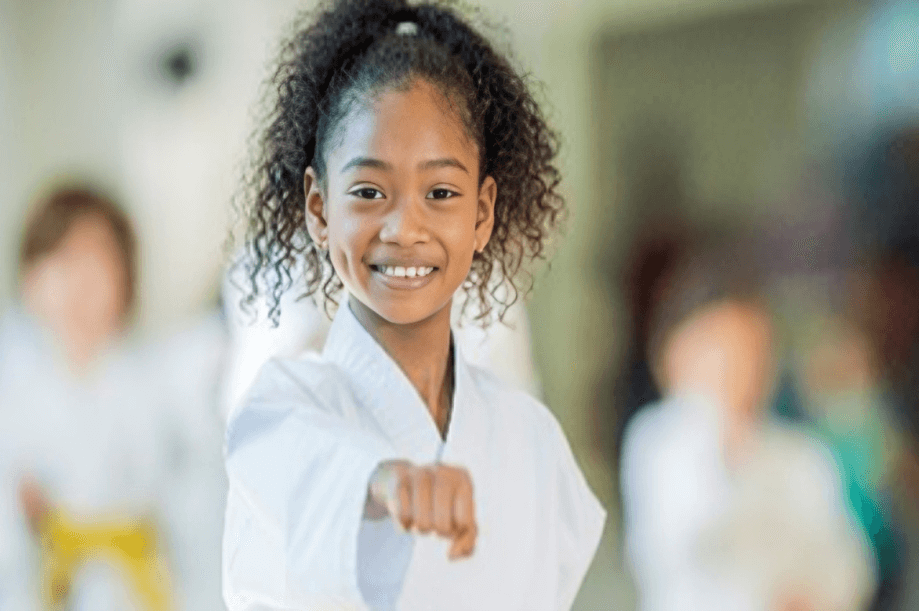 Smiling girl practicing martial arts punch.
