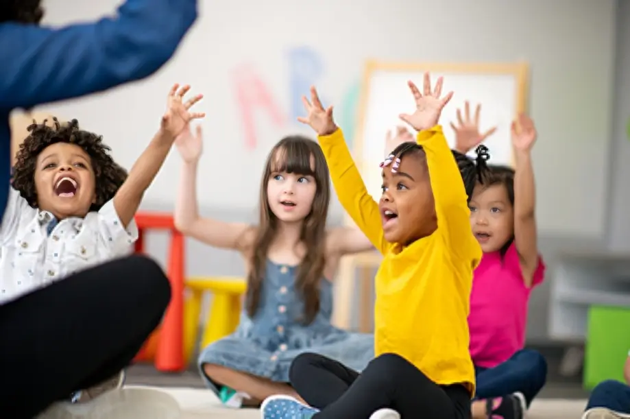 Children raising hands in classroom activity.