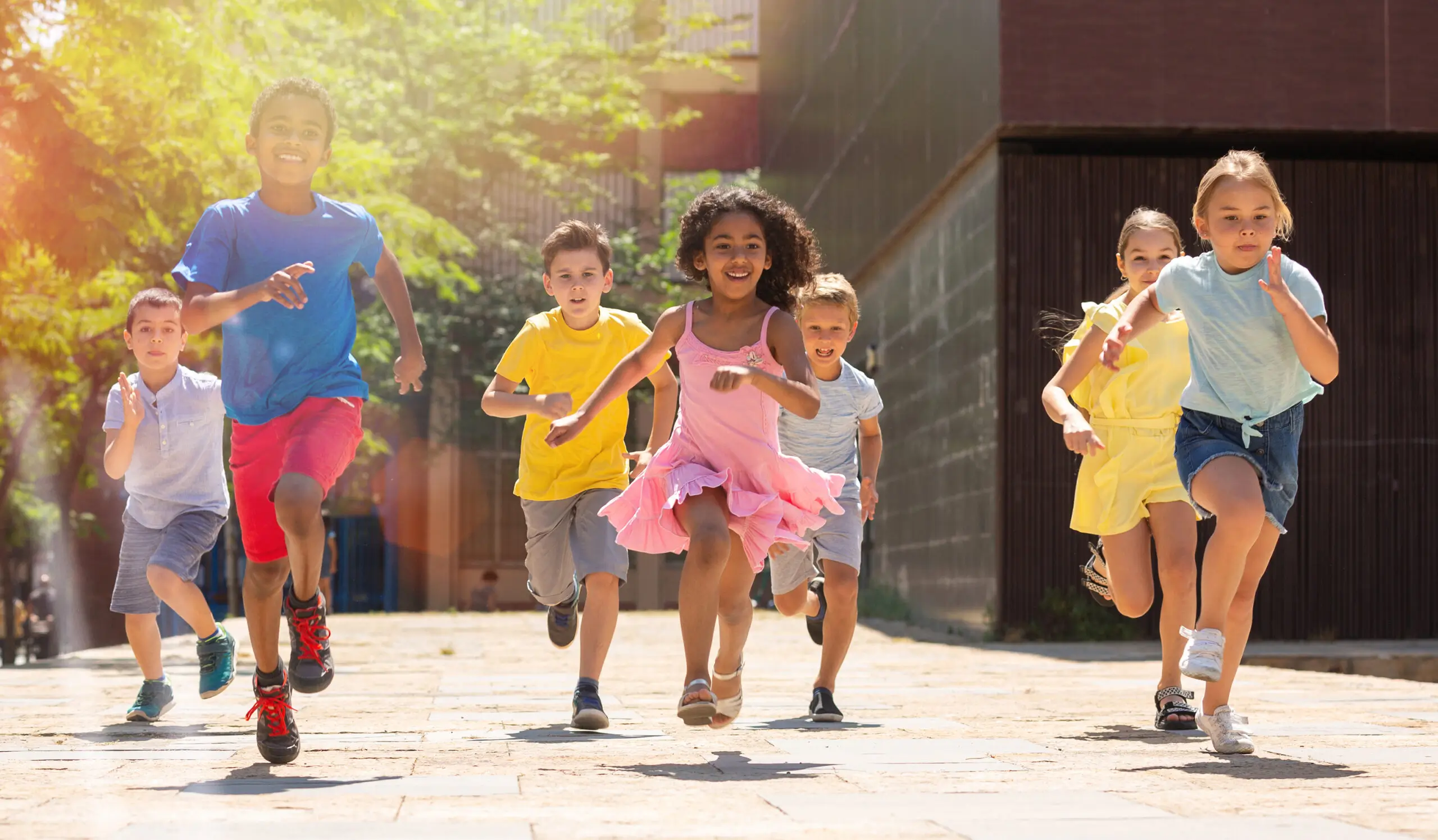 Children joyfully running outdoors on sunny day.